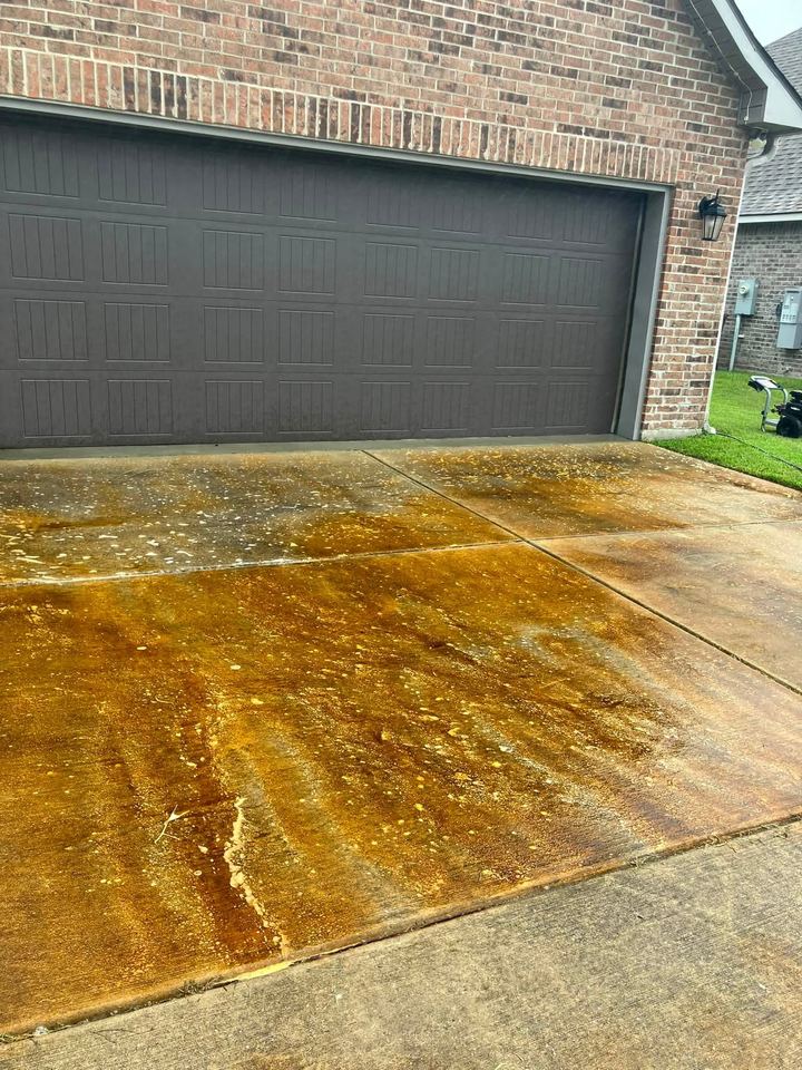 A driveway stained dark orange-brown with rust and dirt, before washing.