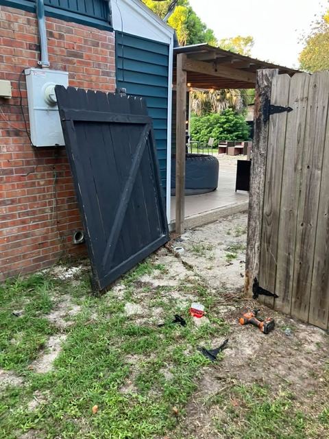 A fence gate taken off its hinges and leaned against the house during a repair, drill on the ground.